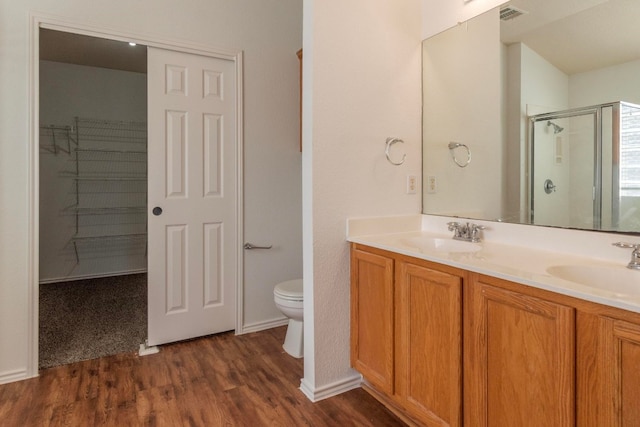 bathroom featuring hardwood / wood-style flooring, walk in shower, vanity, and toilet