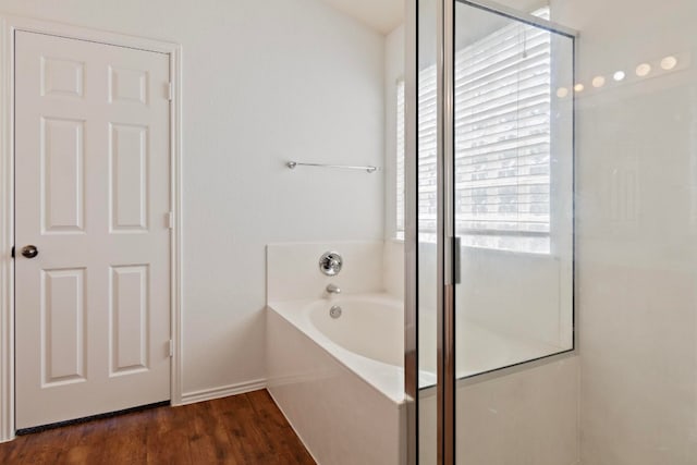 bathroom with wood-type flooring and shower with separate bathtub