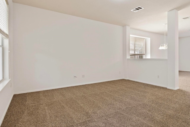 carpeted spare room with a chandelier