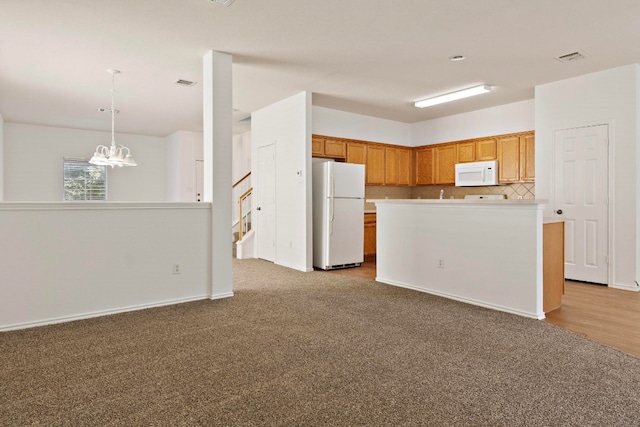 kitchen with tasteful backsplash, white appliances, pendant lighting, light wood-type flooring, and a notable chandelier