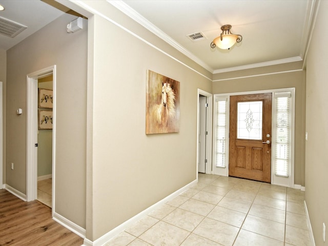 tiled entrance foyer featuring a healthy amount of sunlight and ornamental molding