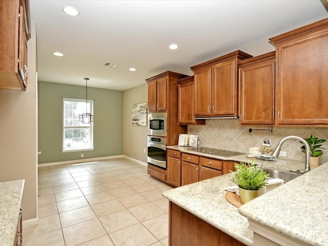 kitchen with sink, stainless steel appliances, tasteful backsplash, light stone counters, and decorative light fixtures