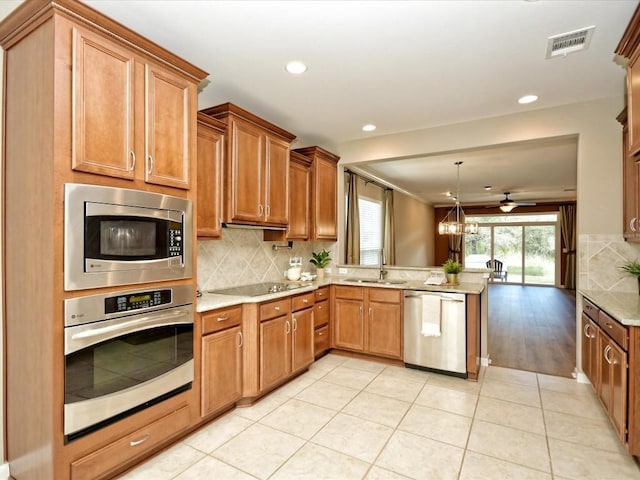 kitchen with appliances with stainless steel finishes, sink, backsplash, hanging light fixtures, and kitchen peninsula