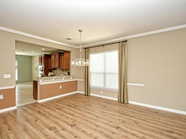 kitchen with pendant lighting, a notable chandelier, kitchen peninsula, crown molding, and light wood-type flooring