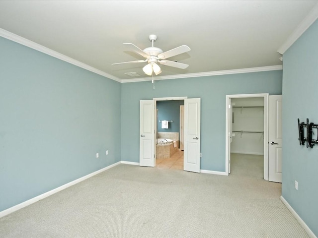 unfurnished bedroom with crown molding, ceiling fan, a walk in closet, light colored carpet, and a closet