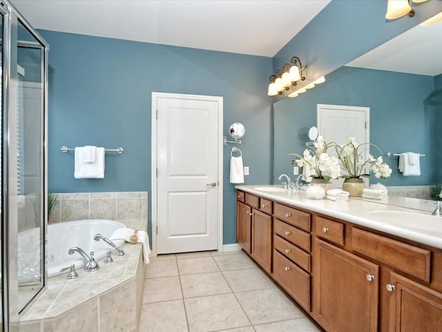 bathroom with tile patterned flooring, vanity, and tiled bath