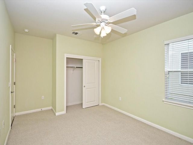 unfurnished bedroom with ceiling fan, light colored carpet, and a closet