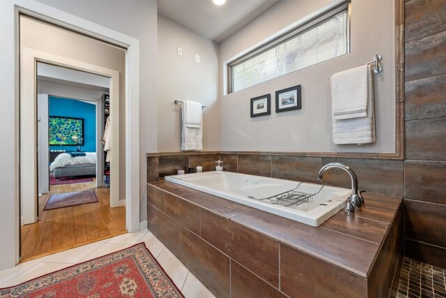 bathroom with tile patterned floors and tiled bath