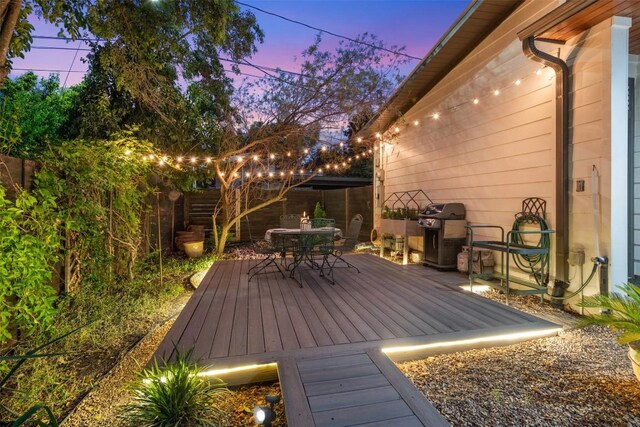 deck at dusk featuring a grill