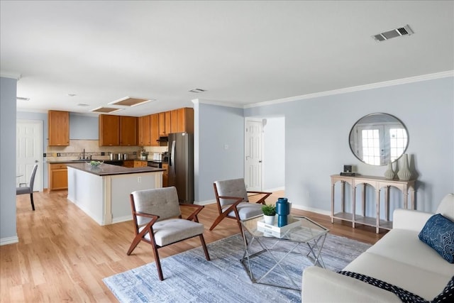 living area featuring ornamental molding, baseboards, visible vents, and light wood finished floors