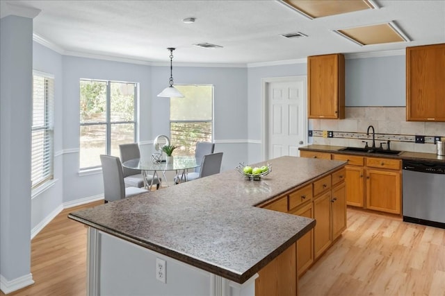 kitchen featuring dishwasher, light wood finished floors, a sink, and a center island