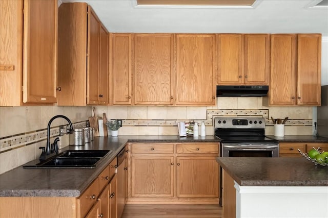 kitchen featuring dark countertops, a sink, stainless steel appliances, under cabinet range hood, and backsplash