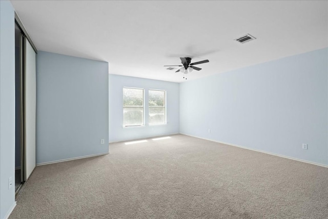 spare room with baseboards, carpet floors, visible vents, and a ceiling fan