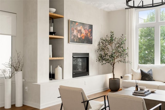 living room with built in shelves, plenty of natural light, and wood finished floors