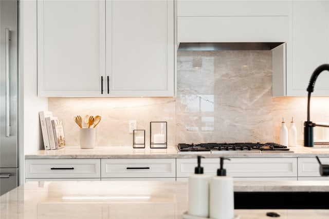 kitchen featuring stainless steel gas cooktop, white cabinets, and decorative backsplash