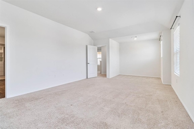 carpeted spare room featuring vaulted ceiling and a healthy amount of sunlight