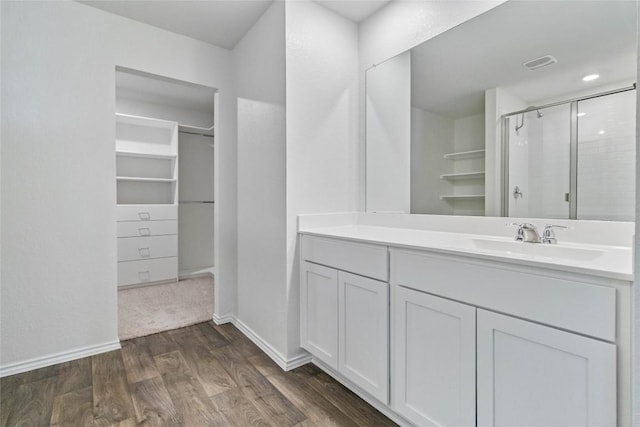 bathroom featuring hardwood / wood-style flooring, vanity, and walk in shower