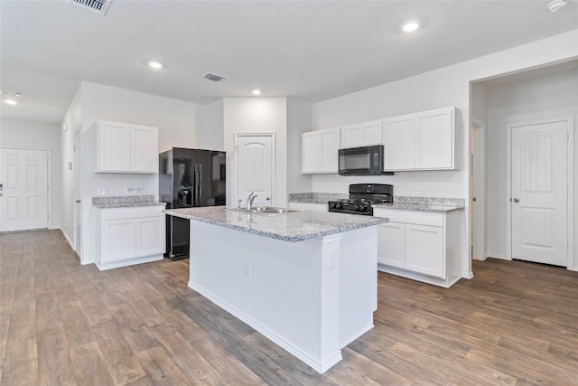 kitchen featuring a kitchen island with sink, white cabinetry, black appliances, and hardwood / wood-style flooring