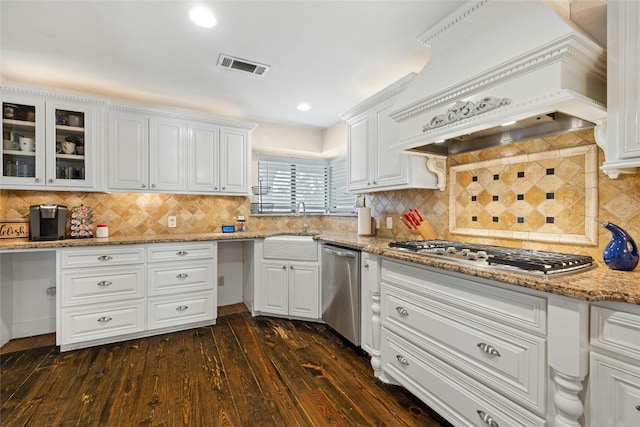 kitchen featuring dark hardwood / wood-style floors, tasteful backsplash, white cabinets, custom exhaust hood, and appliances with stainless steel finishes