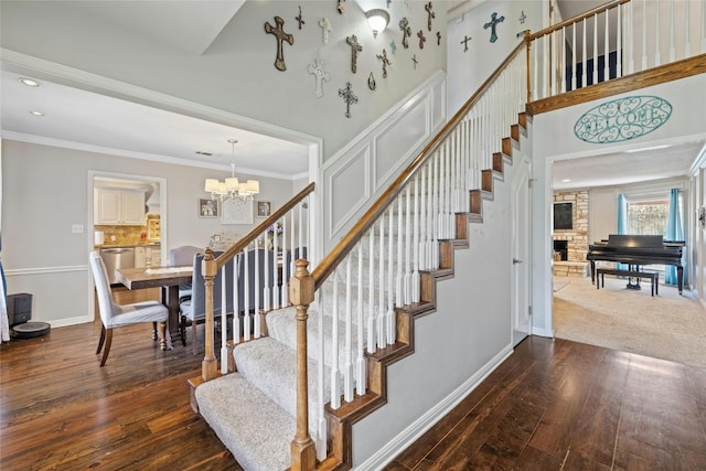 staircase with a notable chandelier, a towering ceiling, hardwood / wood-style floors, and crown molding