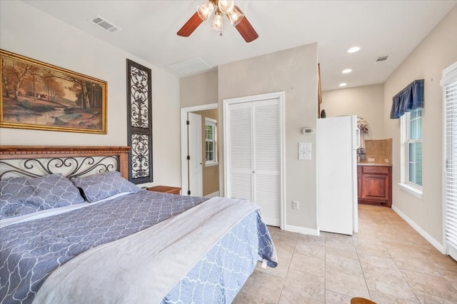 tiled bedroom with ensuite bath, ceiling fan, white refrigerator, and a closet