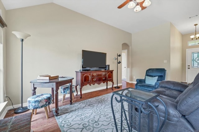 living room with ceiling fan with notable chandelier, vaulted ceiling, and hardwood / wood-style flooring