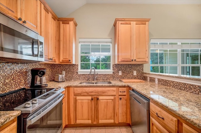 kitchen with appliances with stainless steel finishes, decorative backsplash, light tile patterned flooring, lofted ceiling, and sink