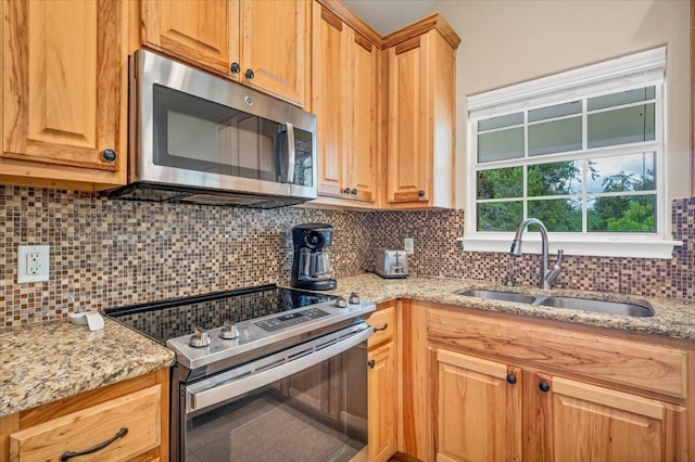 kitchen with light stone counters, tasteful backsplash, sink, appliances with stainless steel finishes, and tile patterned floors