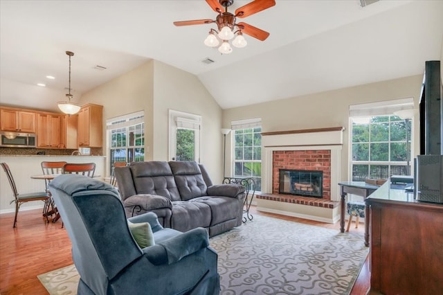 living room with ceiling fan, a fireplace, light hardwood / wood-style floors, and a wealth of natural light