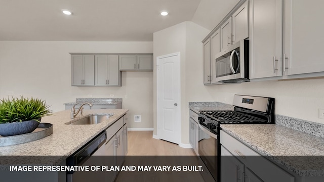 kitchen with gray cabinets, light wood-type flooring, sink, stainless steel appliances, and a center island with sink