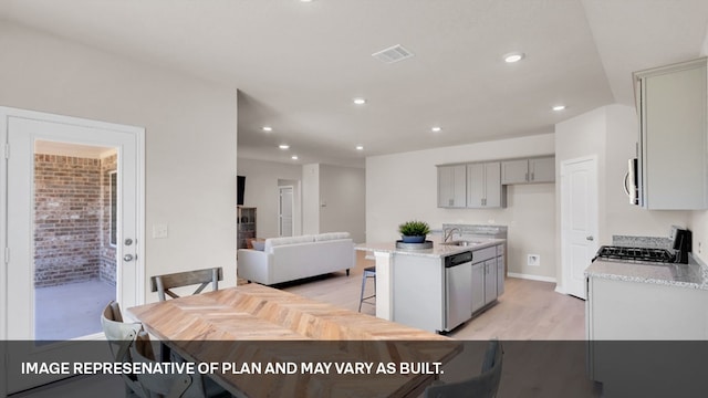 kitchen with gray cabinets, stainless steel appliances, light hardwood / wood-style flooring, a center island with sink, and sink