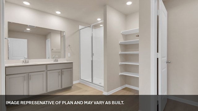 bathroom featuring hardwood / wood-style floors, a shower with door, and vanity