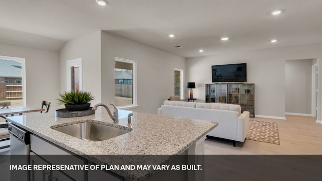 kitchen with dishwasher, lofted ceiling, light hardwood / wood-style flooring, a kitchen island with sink, and sink