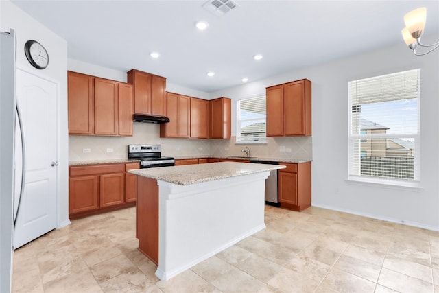 kitchen featuring light stone countertops, stainless steel appliances, a wealth of natural light, and a kitchen island