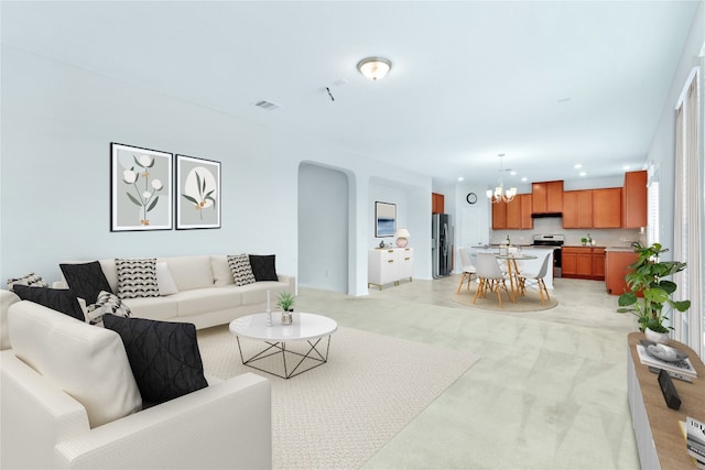 carpeted living room with an inviting chandelier