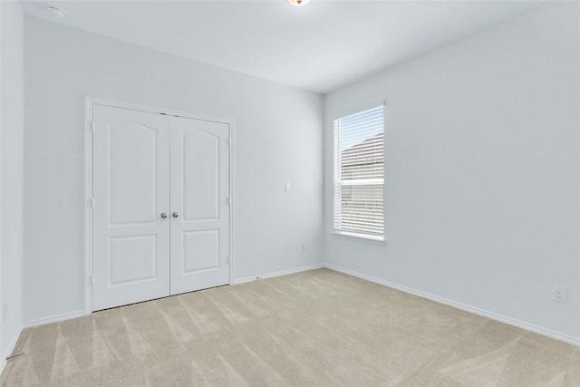 unfurnished bedroom featuring light carpet and a closet