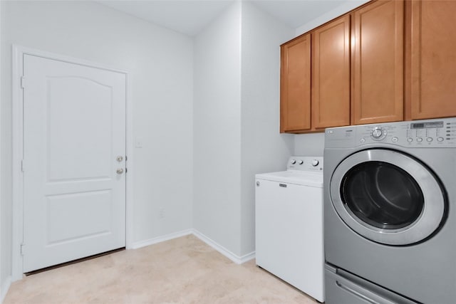 clothes washing area with cabinets and separate washer and dryer