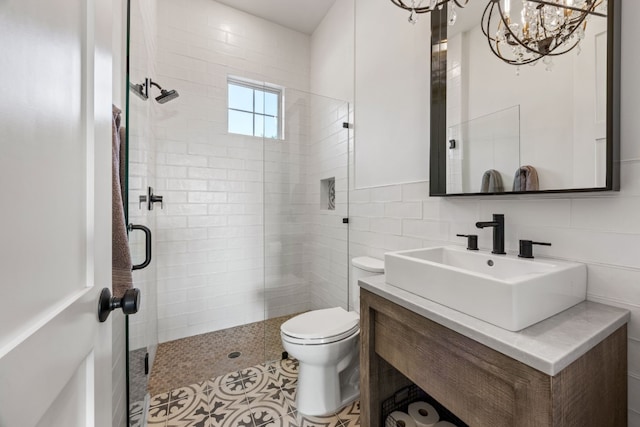 bathroom featuring tile walls, vanity, an inviting chandelier, a shower with door, and toilet