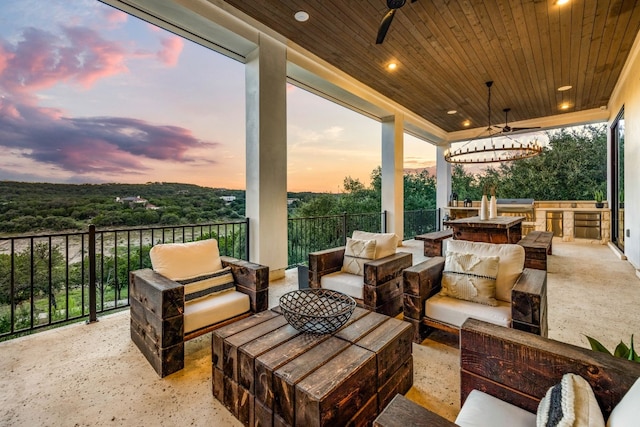 patio terrace at dusk with ceiling fan and an outdoor living space with a fire pit