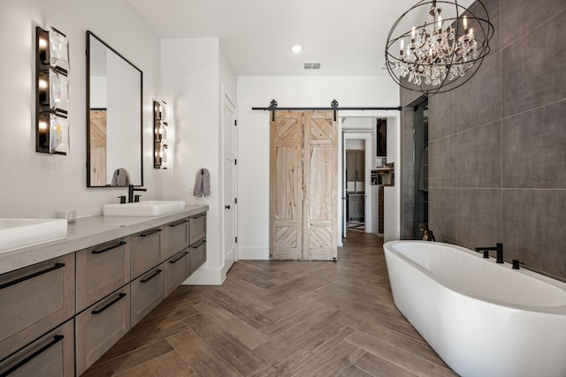 bathroom with an inviting chandelier, vanity, a bathing tub, and parquet floors