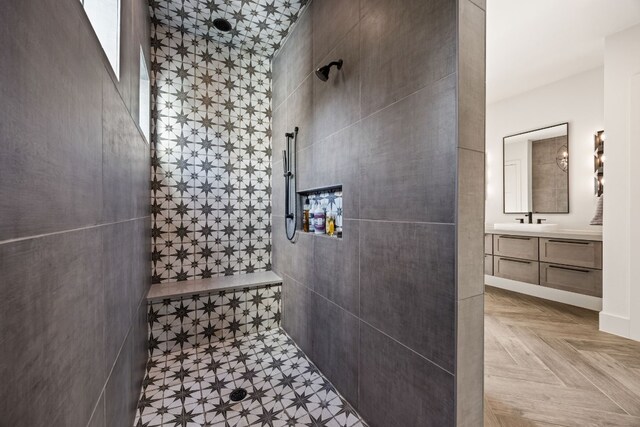 bathroom with a tile shower, tile walls, parquet flooring, and vanity