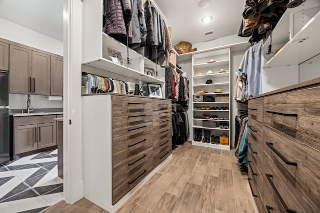 walk in closet with sink and light hardwood / wood-style floors