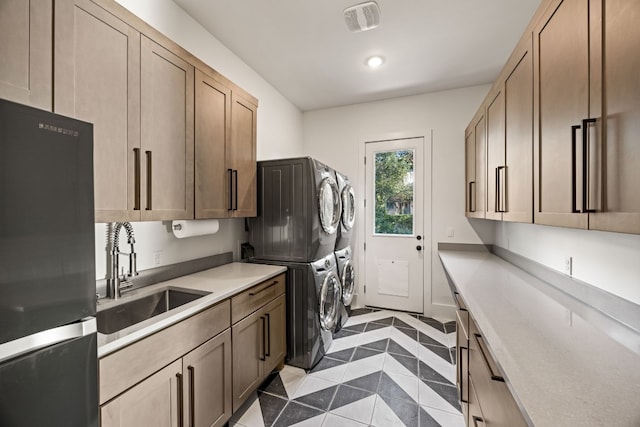 interior space featuring black refrigerator, stacked washer / drying machine, light tile patterned floors, and sink