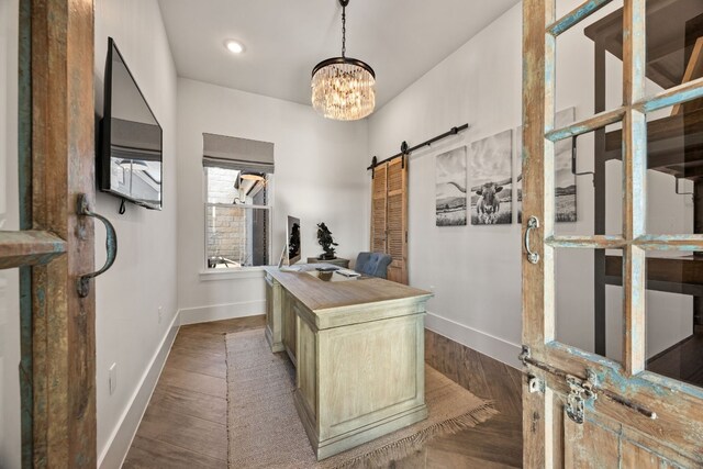 office space featuring a barn door, dark hardwood / wood-style flooring, and a notable chandelier