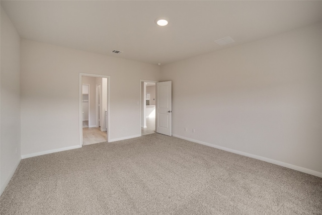 unfurnished bedroom featuring a walk in closet and light colored carpet