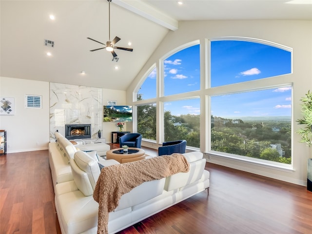 living room with a healthy amount of sunlight, dark wood-type flooring, a premium fireplace, and ceiling fan