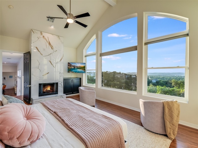 bedroom featuring wood-type flooring, a fireplace, multiple windows, and ceiling fan