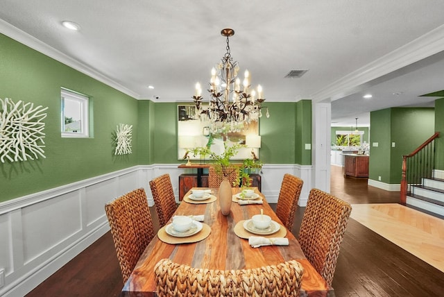 dining room with visible vents, a wainscoted wall, wood finished floors, stairway, and an inviting chandelier