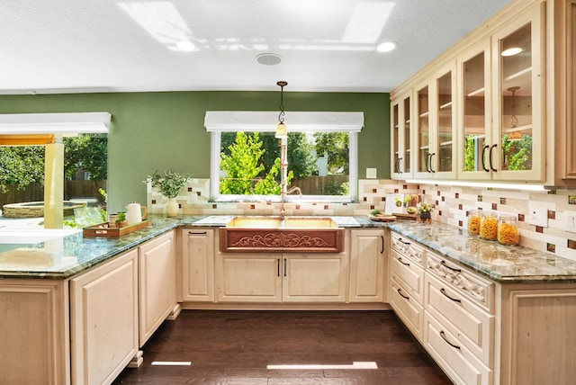 kitchen featuring a sink, glass insert cabinets, cream cabinets, dark wood-style floors, and decorative backsplash