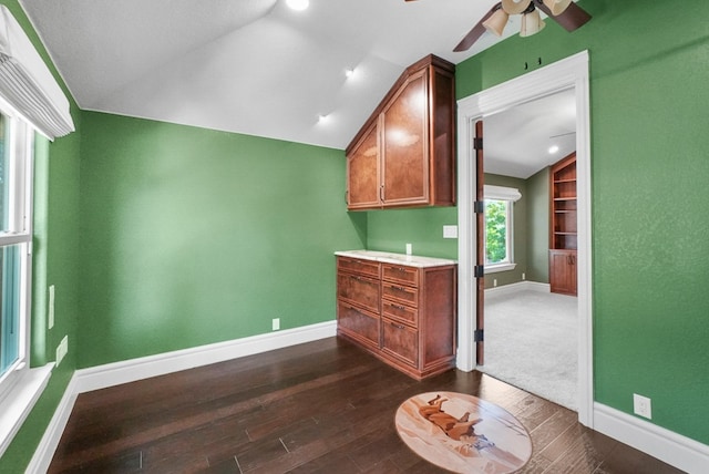 interior space with baseboards, ceiling fan, dark wood finished floors, and vaulted ceiling